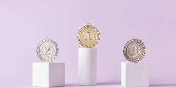 Photo by DS stories: https://www.pexels.com/photo/medals-on-pedestal-on-pink-studio-background-7267588/